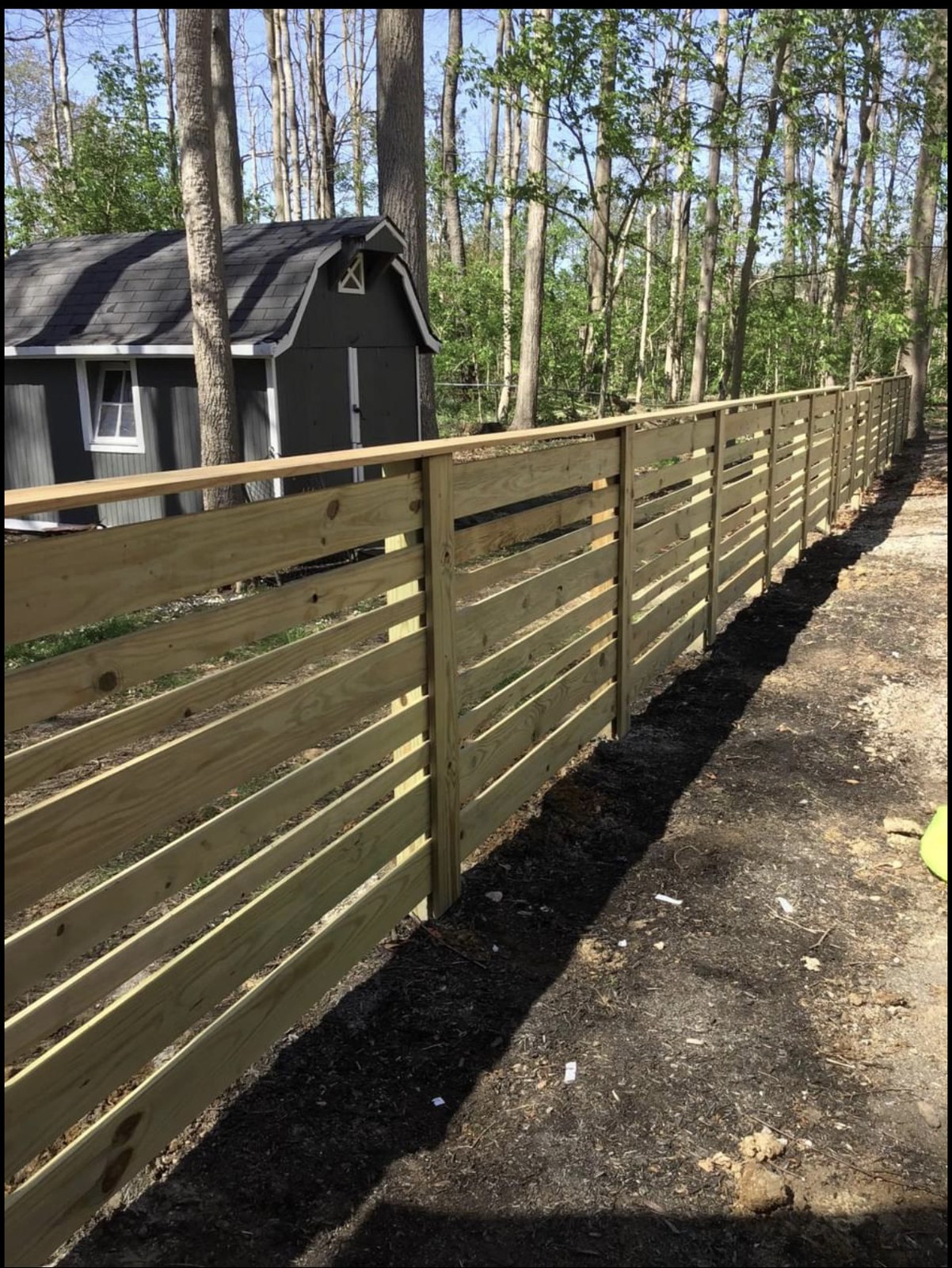 Horizontal wood fence: Horizontal boards along a wooded property.